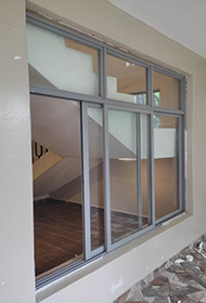 Sample grey aluminium sliding window with three sliding panels and top fixed glass partition